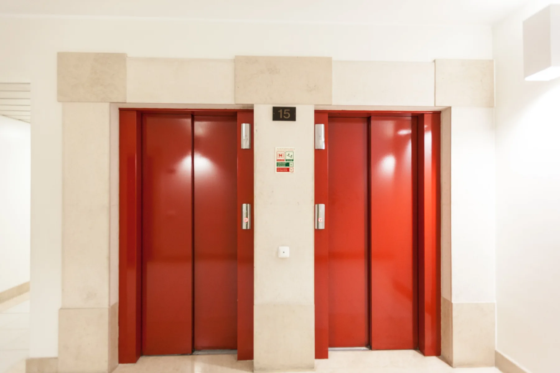 Un vestíbulo interior con dos puertas rojas de ascensor.