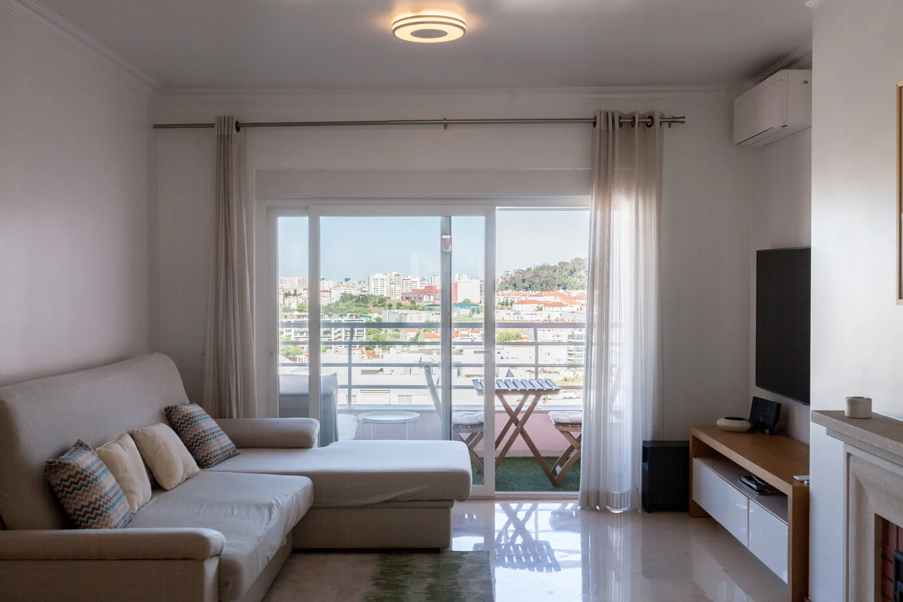 Una sala de estar con asientos junto a grandes ventanales con vistas a la ciudad.