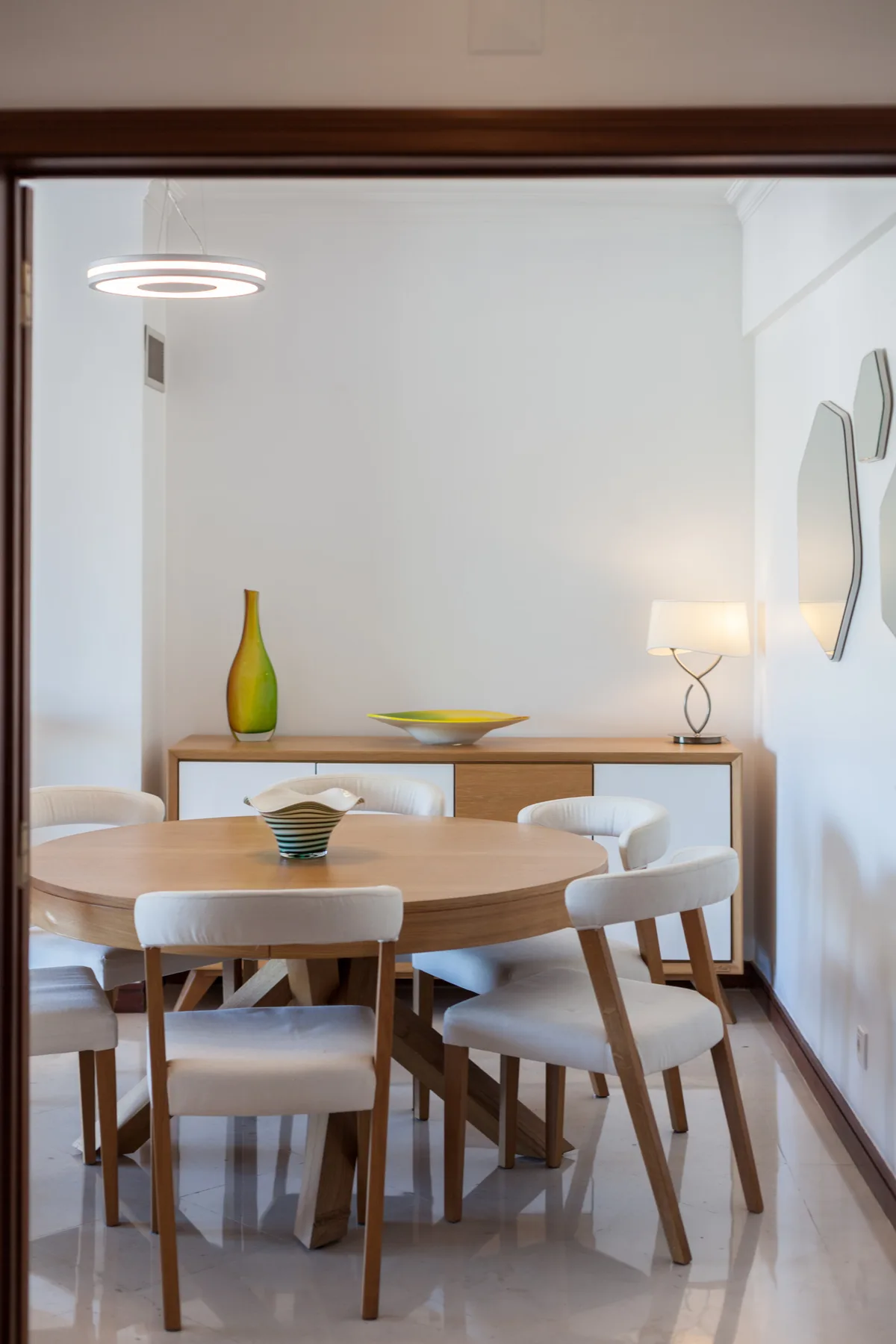 Comedor con una mesa redonda, sillas y un aparador.