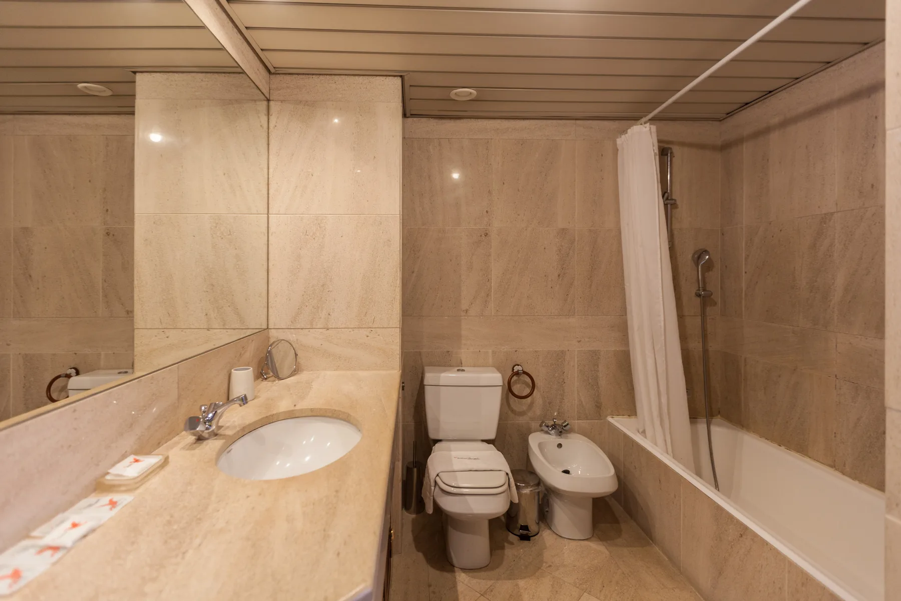Un baño revestido de azulejos con lavabo, inodoro, bidé y bañera.