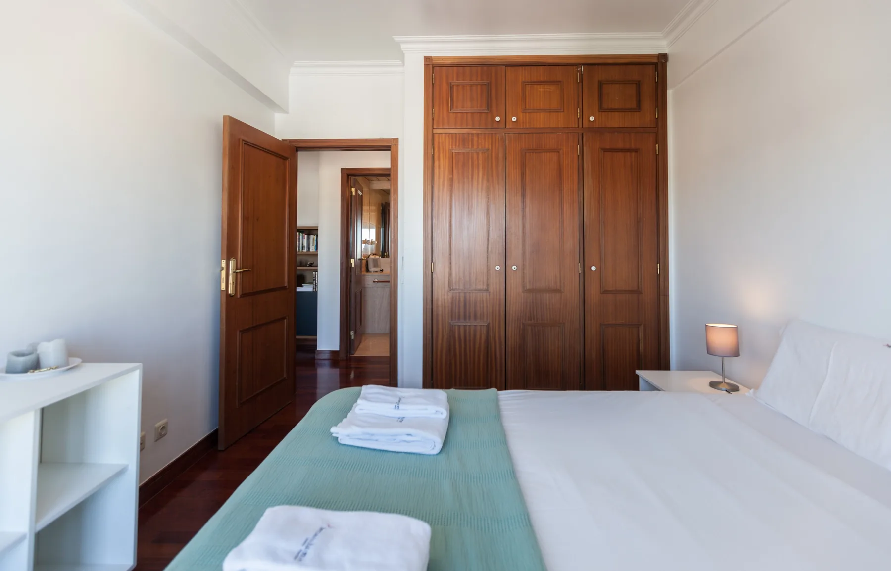 Un dormitorio con un gran armario de madera y una cama bien tendida.