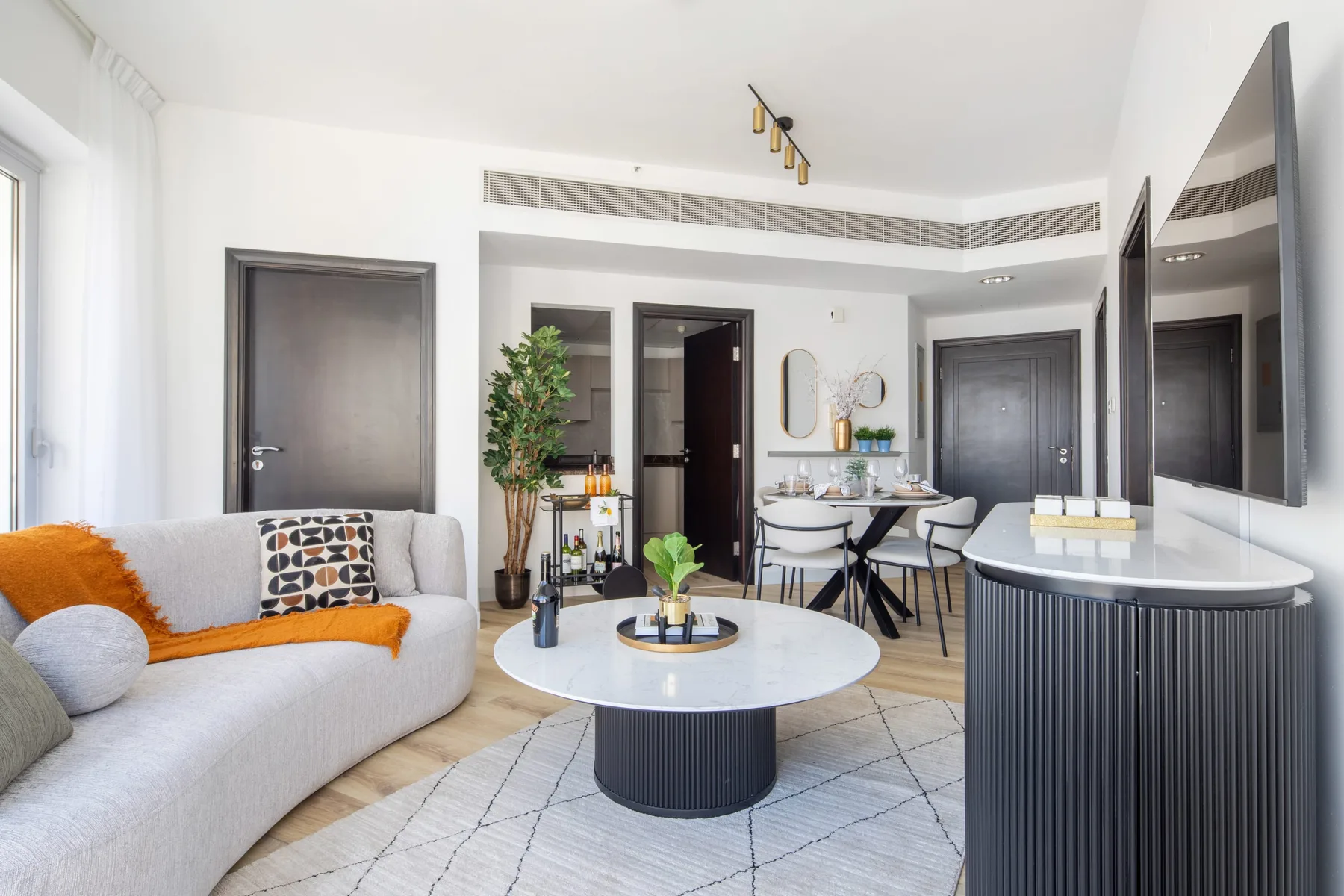 A bright modern living and dining area with a curved sofa and round coffee table.