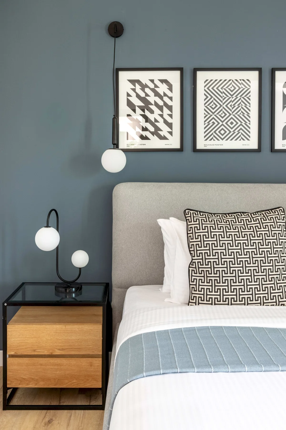 A bedroom with a neatly made bed, patterned pillows, and framed wall art.
