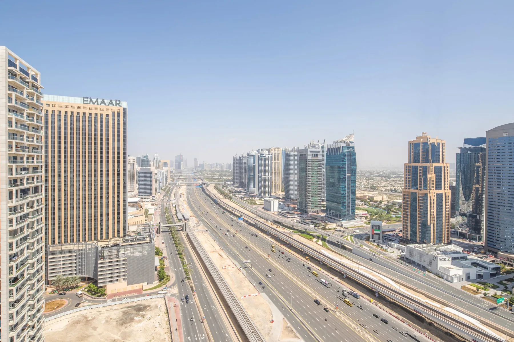A city skyline rises beside a wide highway under a clear sky.