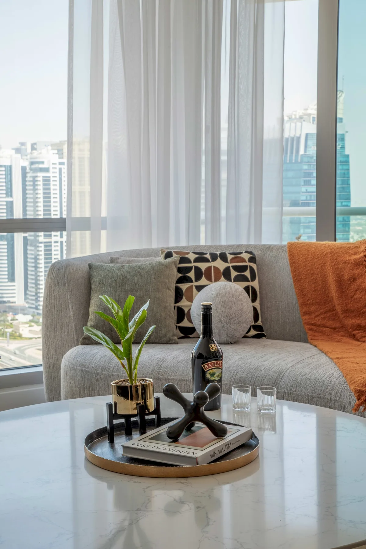 A bright living room with a gray sofa, large windows, and a coffee table.