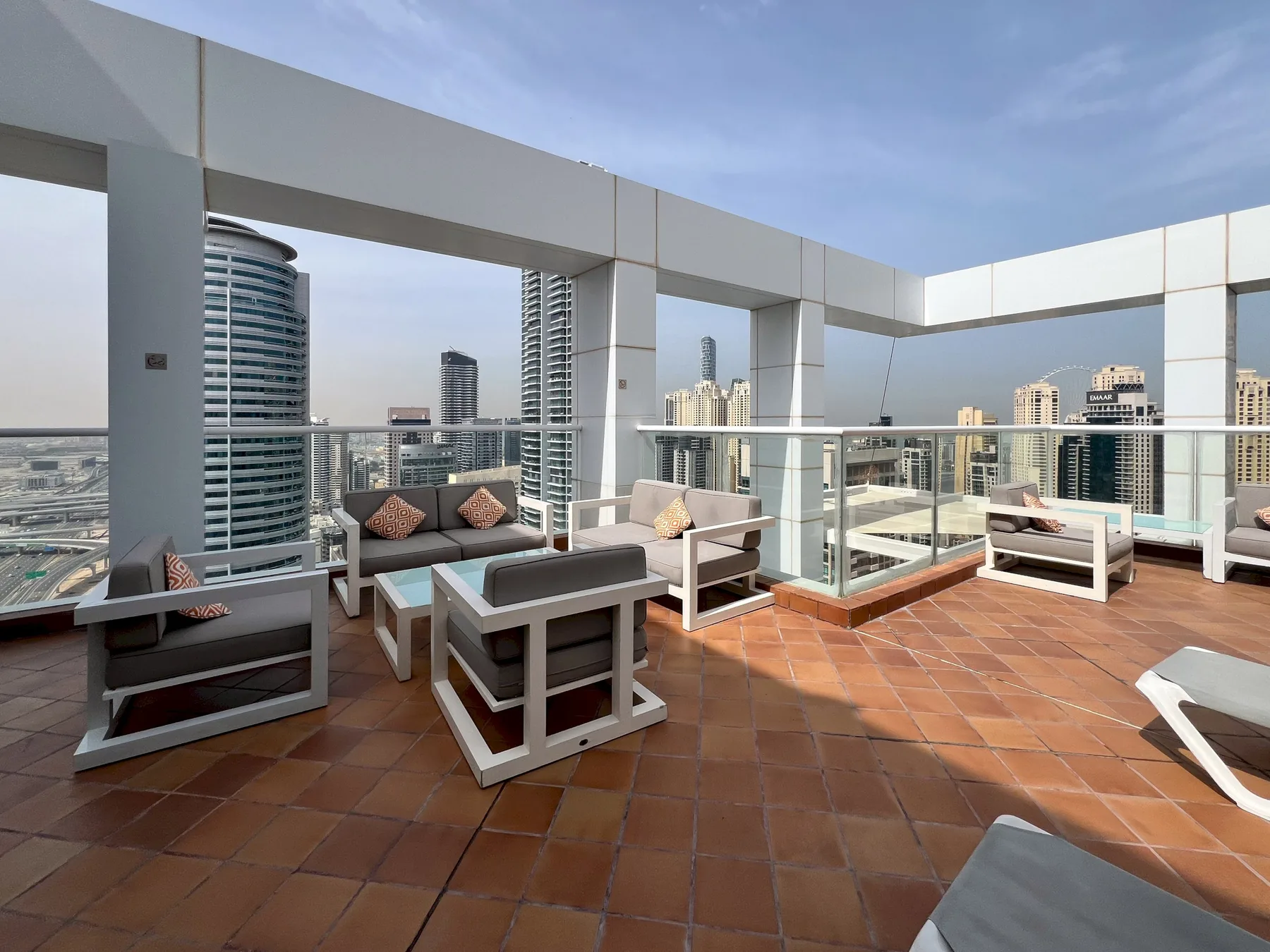 A rooftop terrace with outdoor seating and a glass railing overlooking the city.