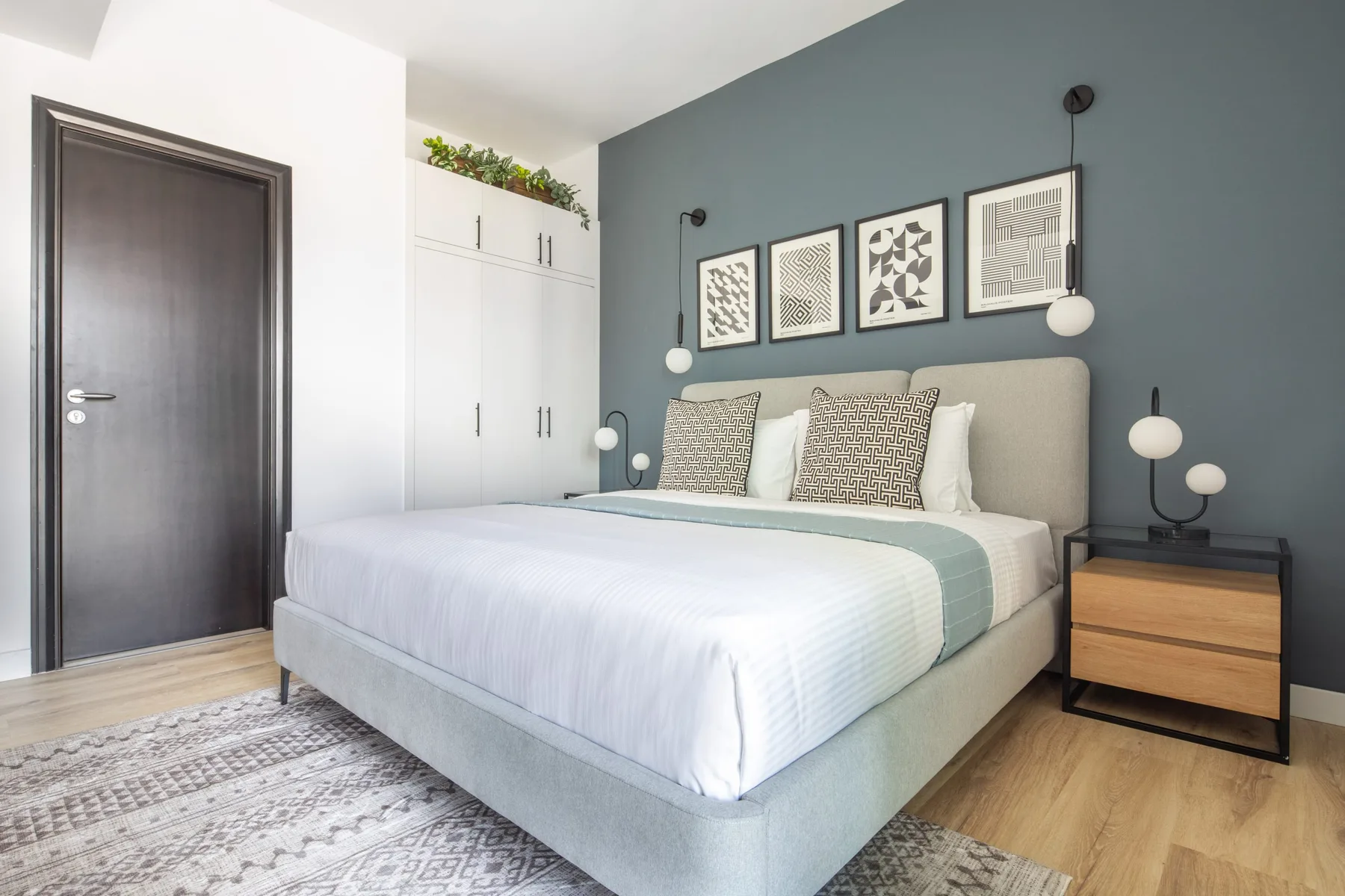 A bedroom with a neatly made bed, framed wall art, and bedside tables.
