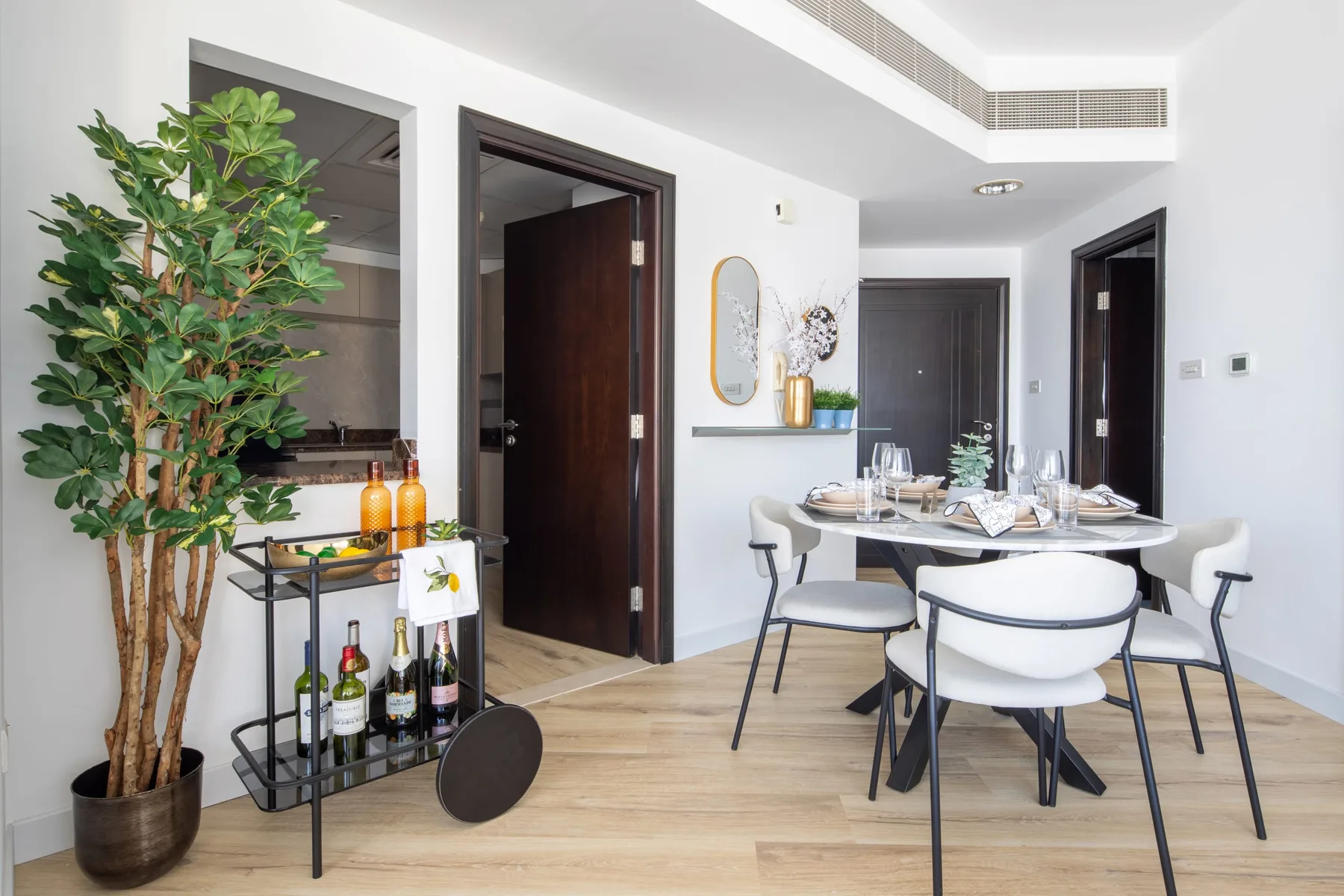 A dining area with a set table and a leafy plant beside the doorway.