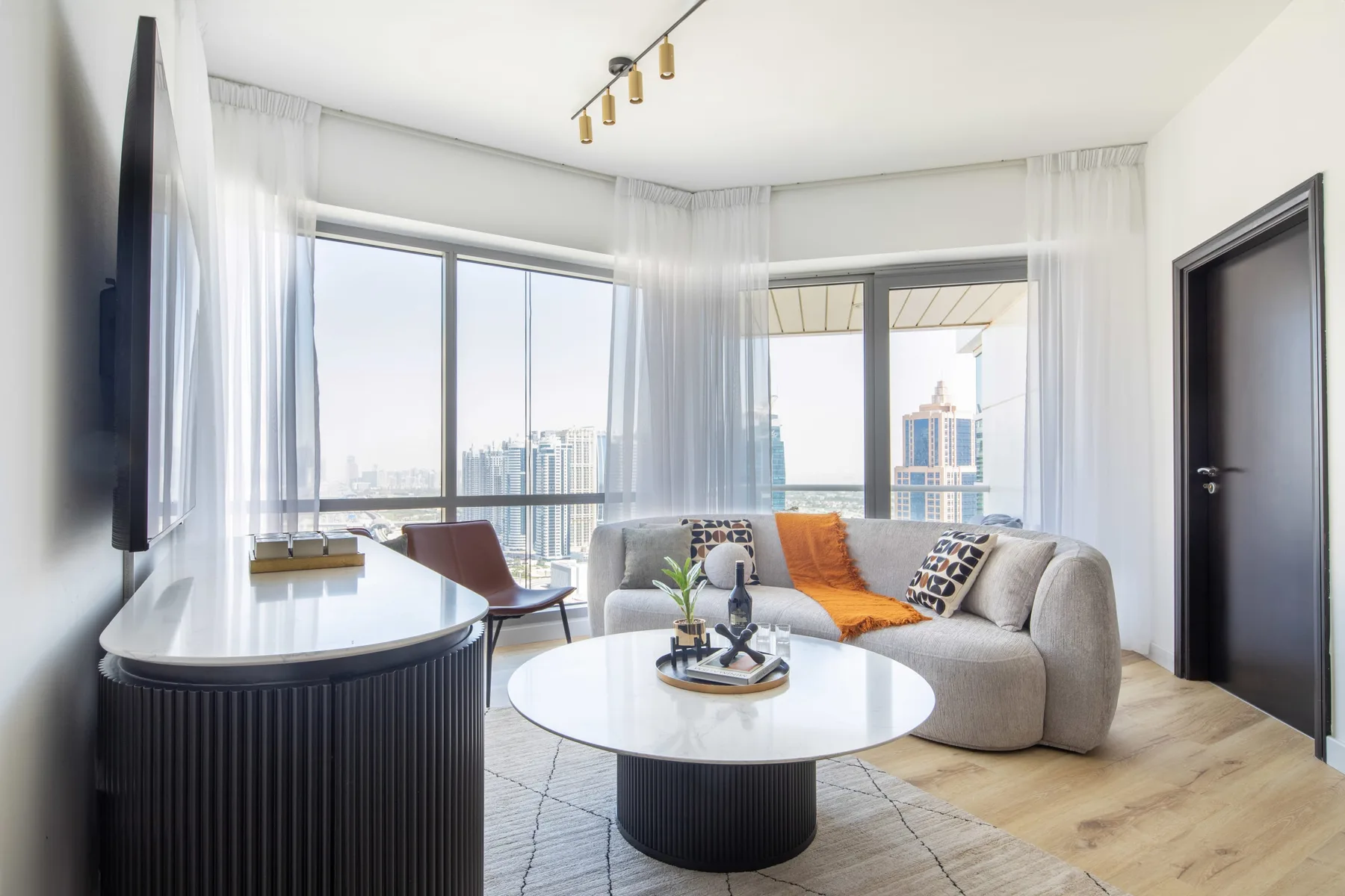 A bright living room with a curved seating area and large windows overlooking the city.