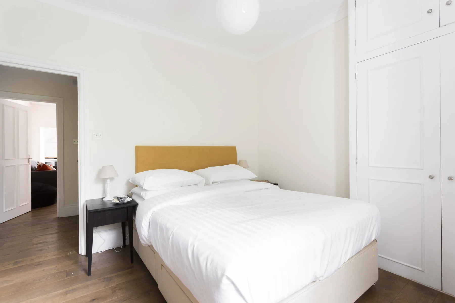 A bright bedroom with a bed beside a small bedside table.