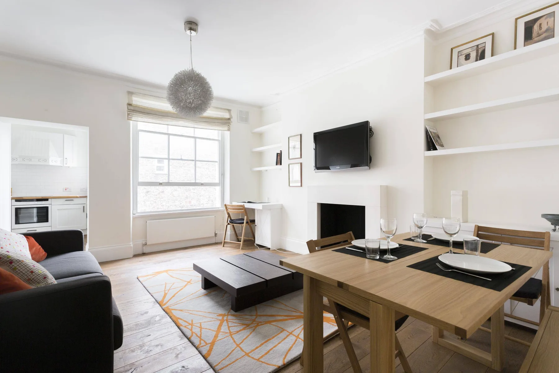 A bright living and dining area with a table, seating, and a television.