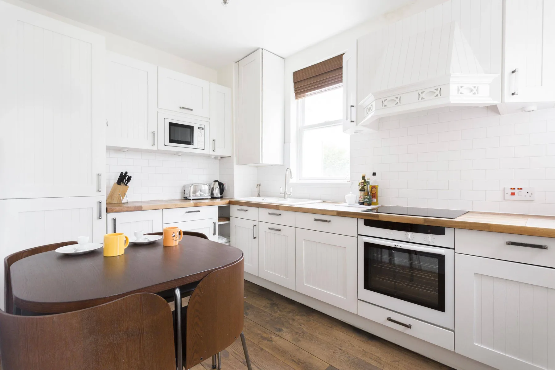 A bright kitchen with white cabinets, a countertop, and a dining table.