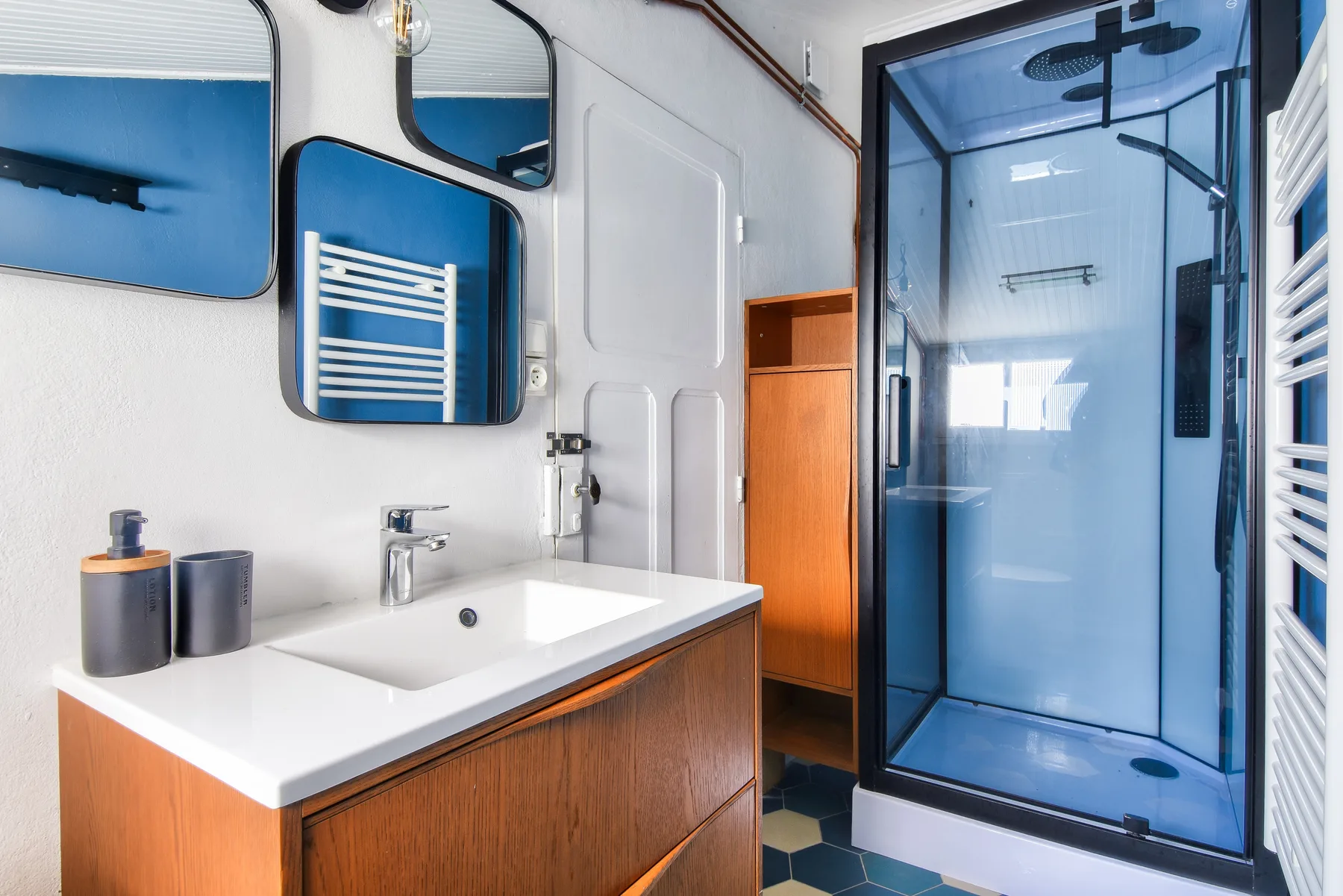 A bathroom with a sink and a glass-enclosed shower.