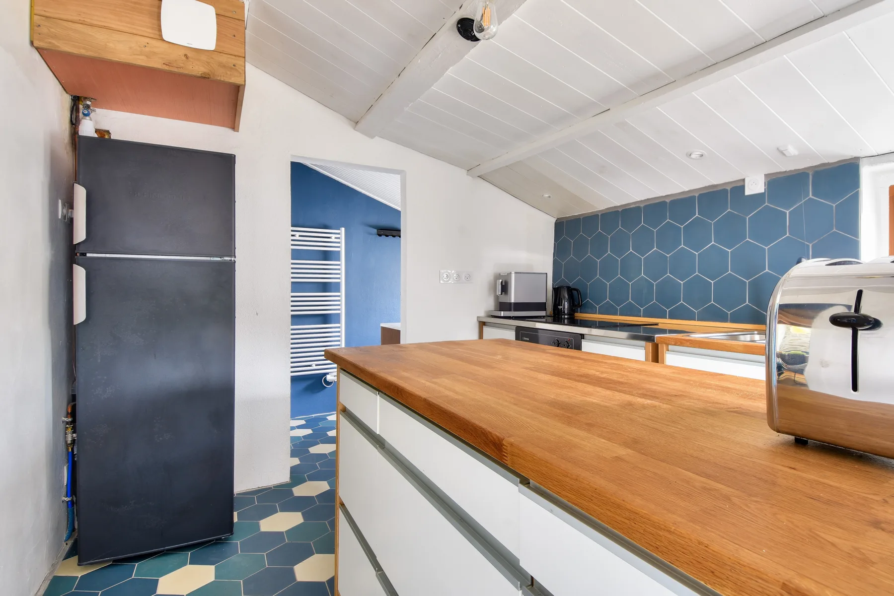 Kitchen with a wooden countertop and blue hexagonal tile backsplash.