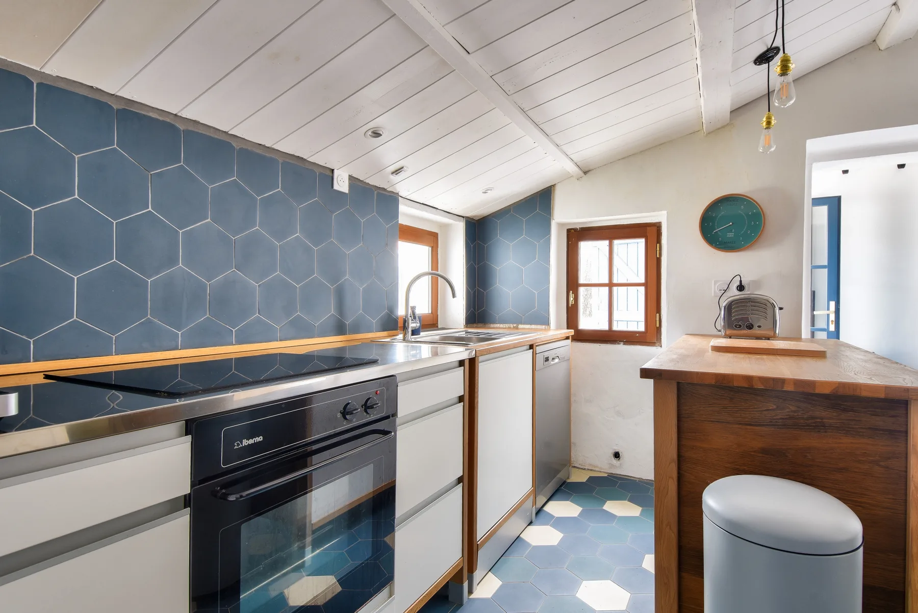 Kitchen with blue hexagonal tile backsplash and a wooden island.