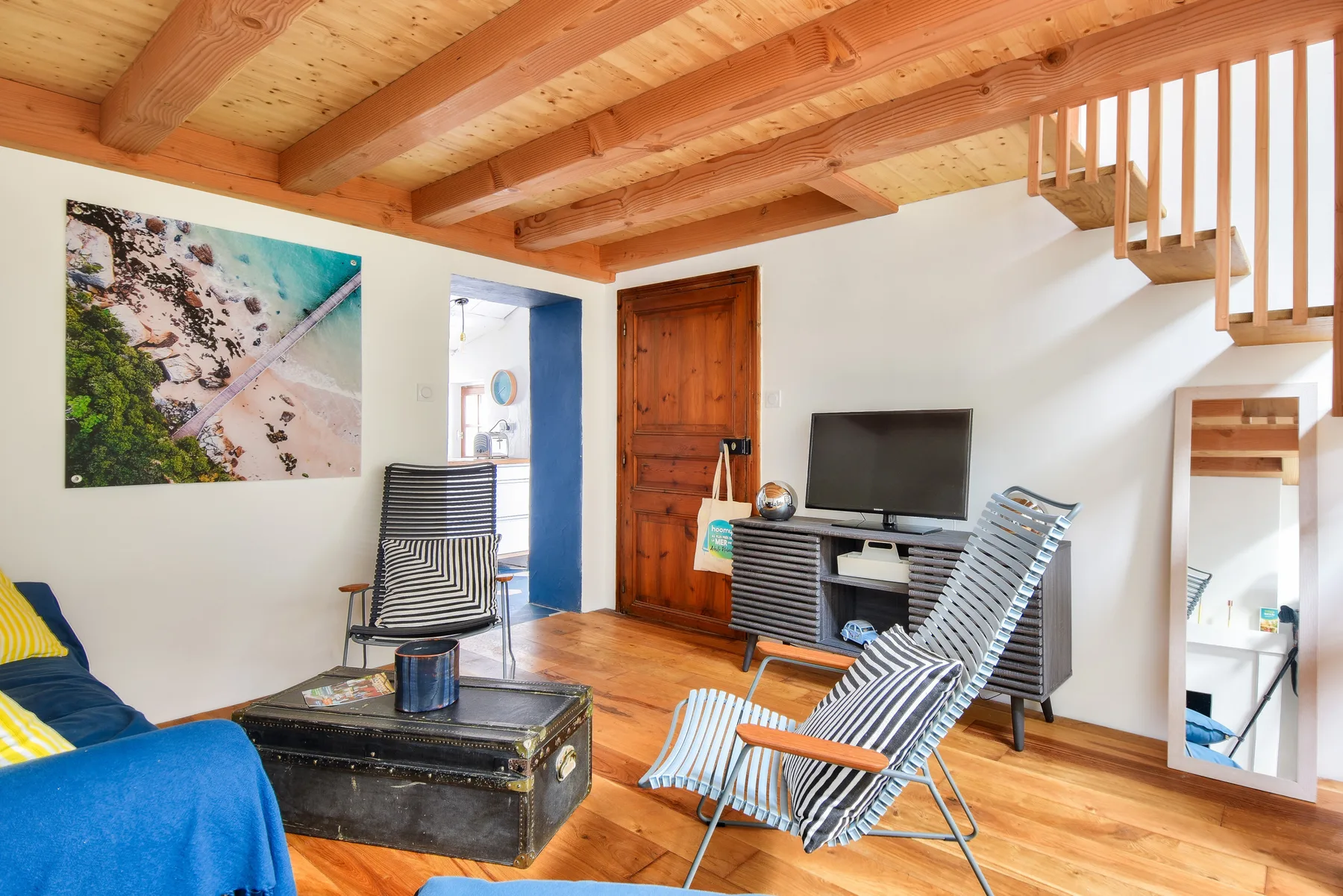 Living room with seating, a television, and a wooden staircase.