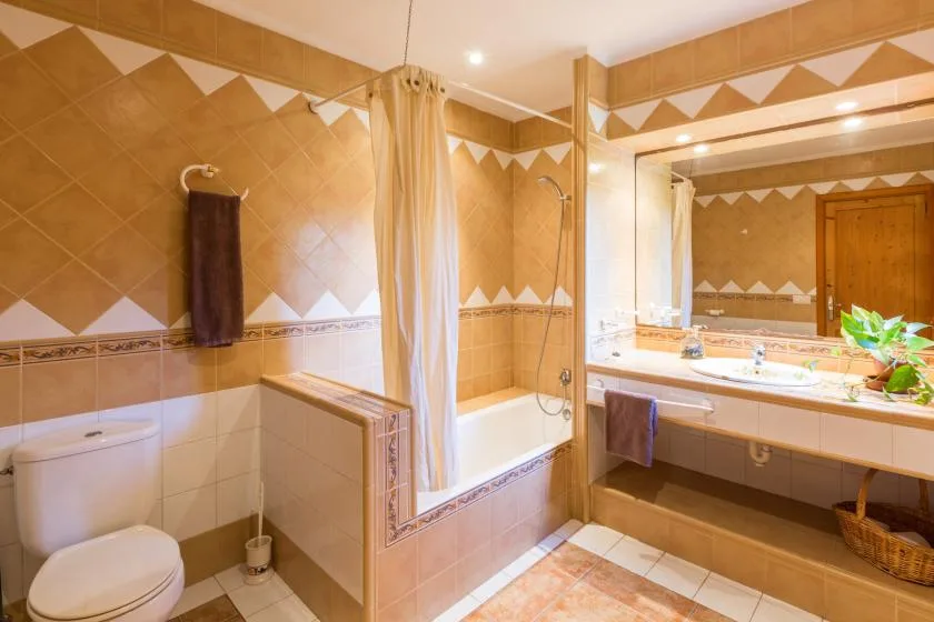 Un baño alicatado con bañera, cortina de ducha y una amplia encimera de lavabo.