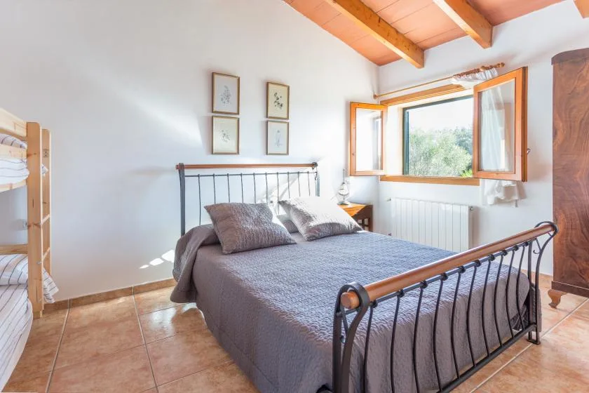 Un dormitorio con una cama doble, una litera y una ventana abierta.