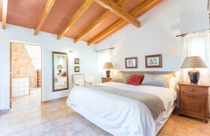 Un dormitorio con una cama grande bajo vigas de madera a la vista.