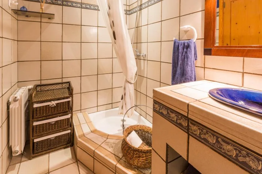 Un baño alicatado con bañera, cortina de ducha y lavabo.