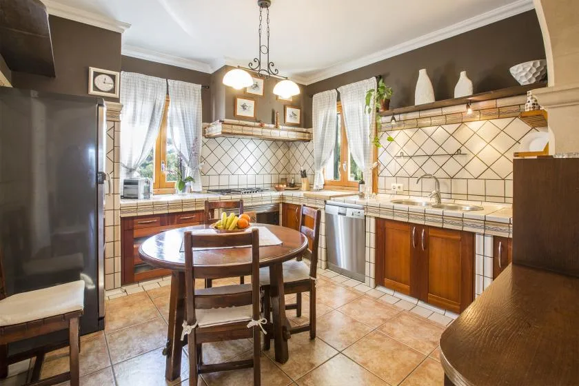 Una cocina con encimeras de azulejos, armarios de madera y una pequeña mesa de comedor.