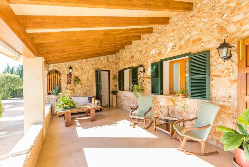 Una terraza con paredes de piedra, vigas de madera y asientos junto a la pared.