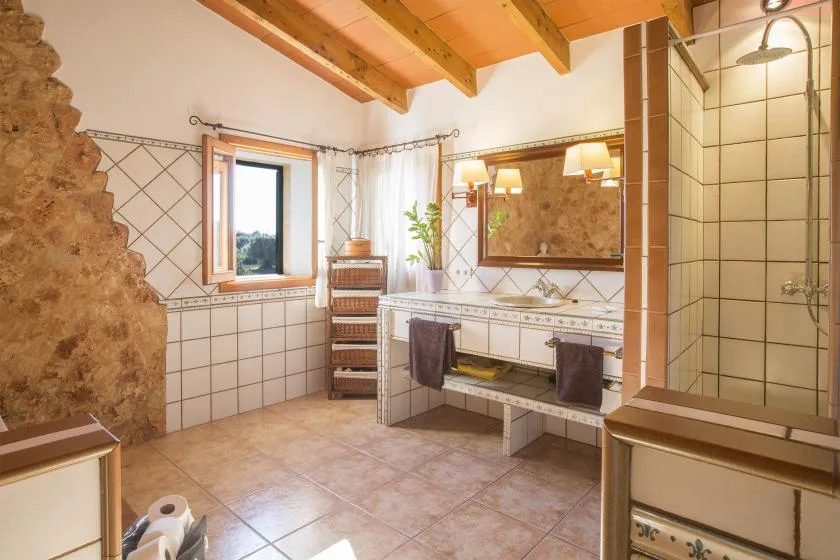 Un baño con azulejos, lavabo, espejo grande y ducha de vidrio.