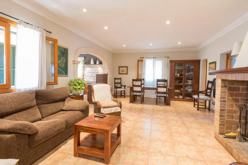 Una luminosa sala de estar y comedor con asientos, una mesa de madera y una chimenea.