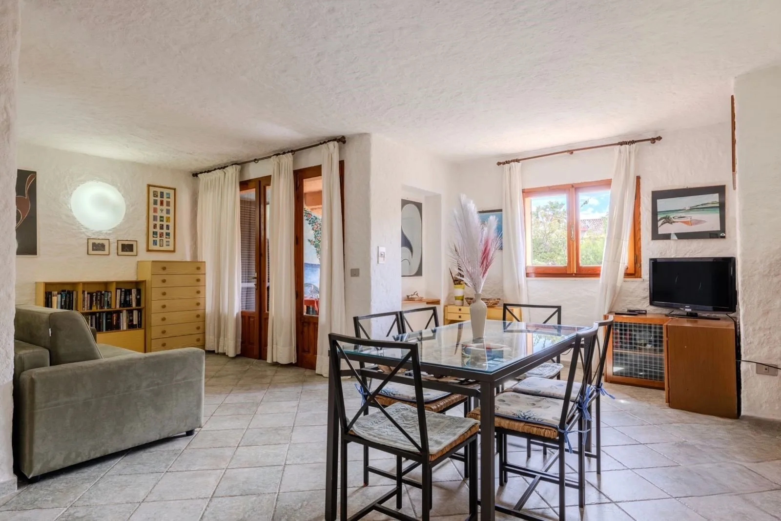 A bright living and dining room with a glass dining table and seating.