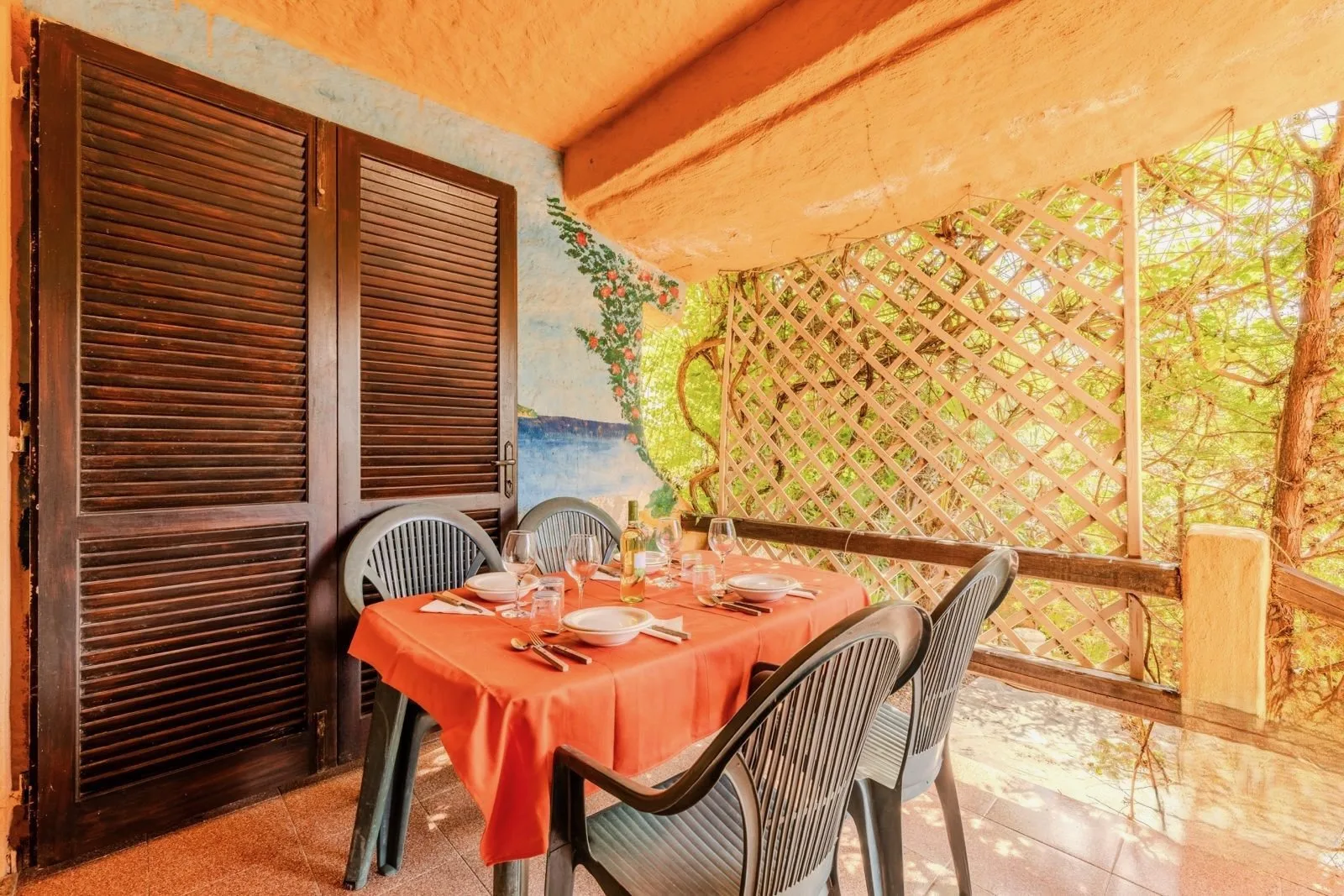 Comedor en un patio cubierto, con una mesa junto a una celosía de madera.