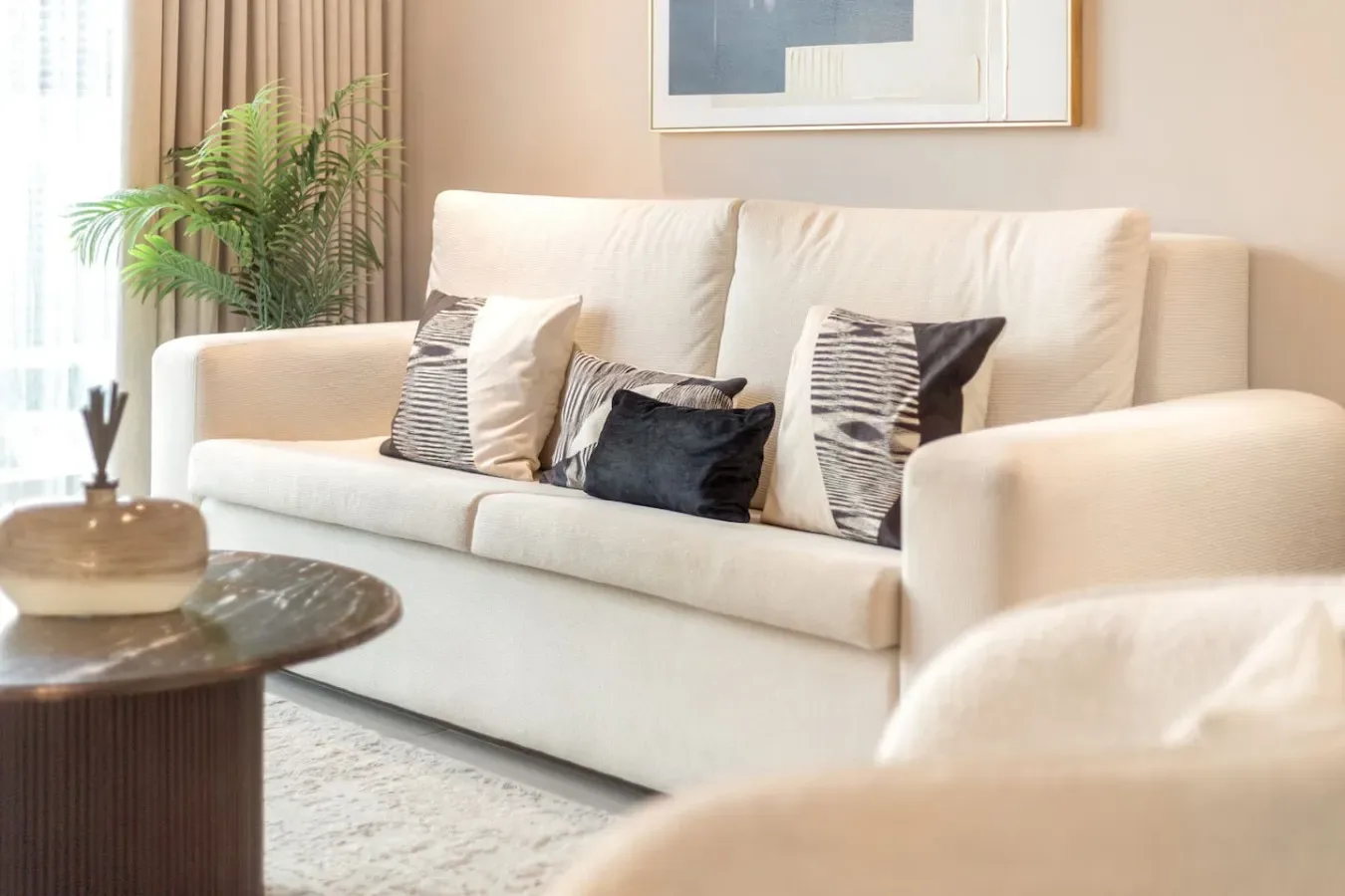 A bright living room with a cream sofa and patterned cushions.