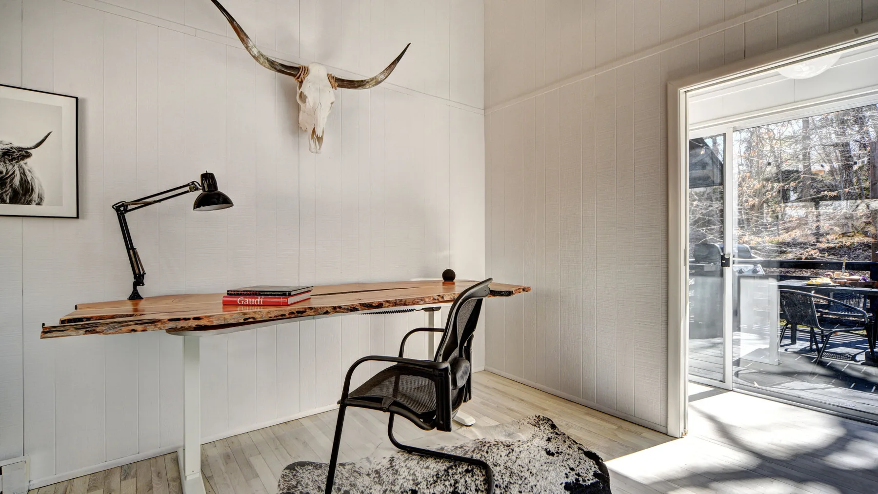 Un espacio de trabajo luminoso con un escritorio largo de madera y una ventana grande.