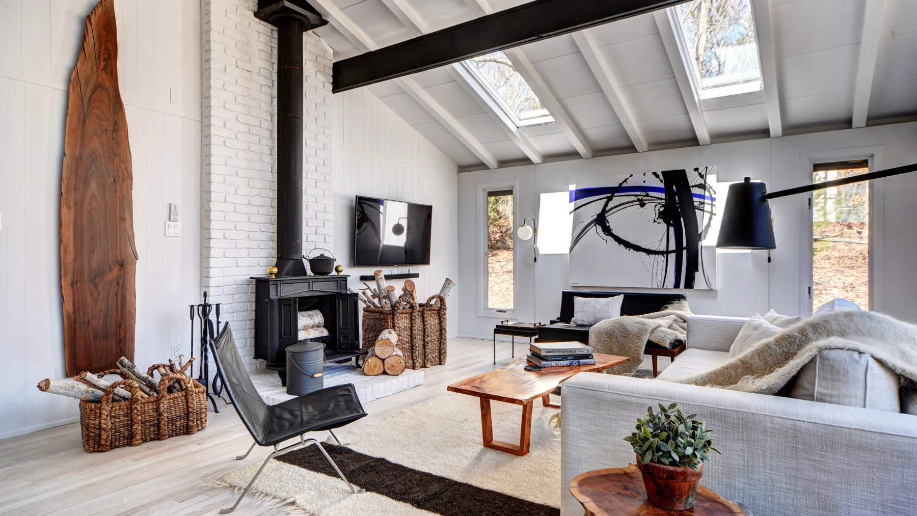Una sala luminosa con chimenea, asientos y techo inclinado con tragaluces.