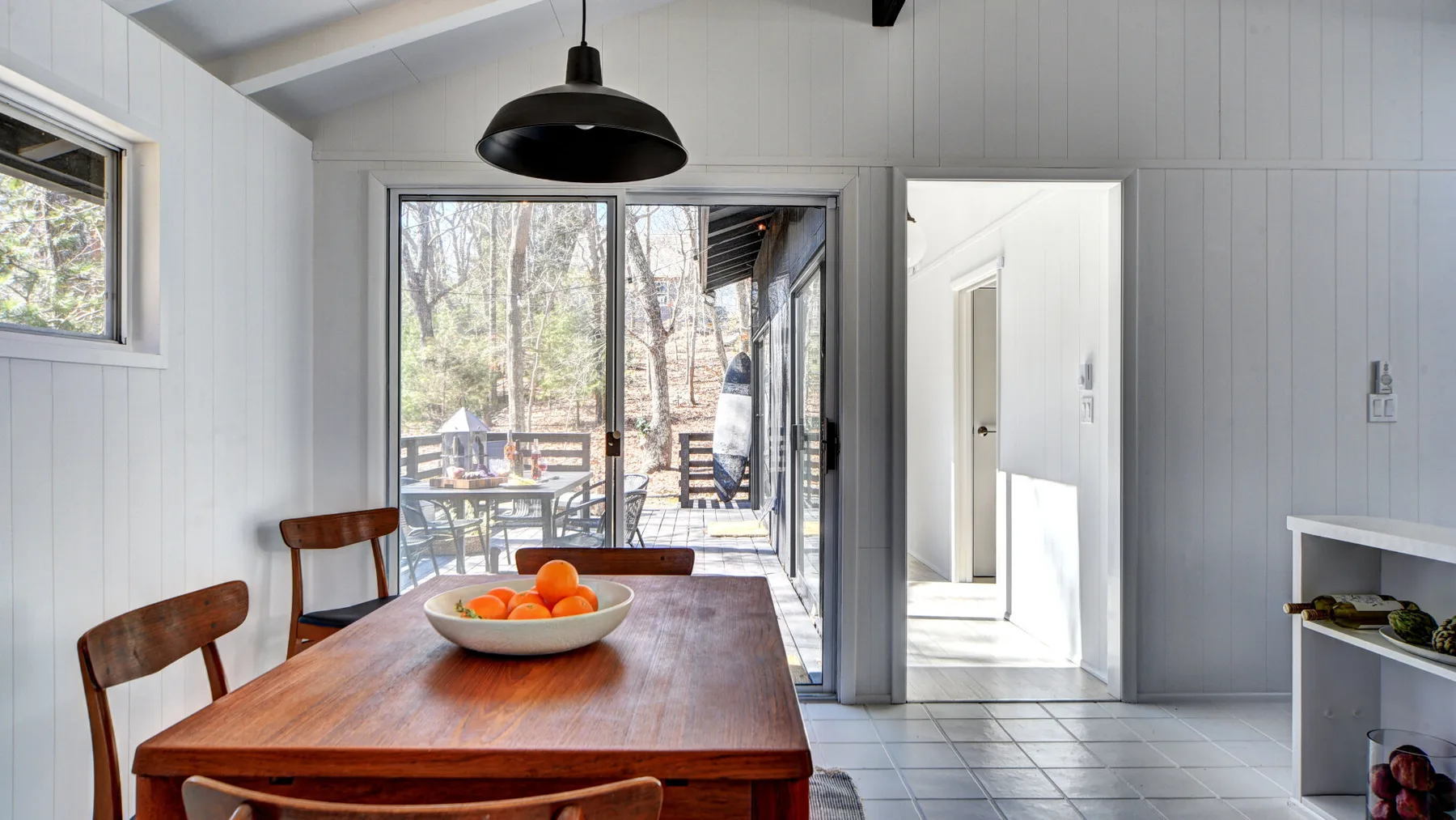 Comedor con una mesa de madera junto a puertas de vidrio que dan a una terraza.