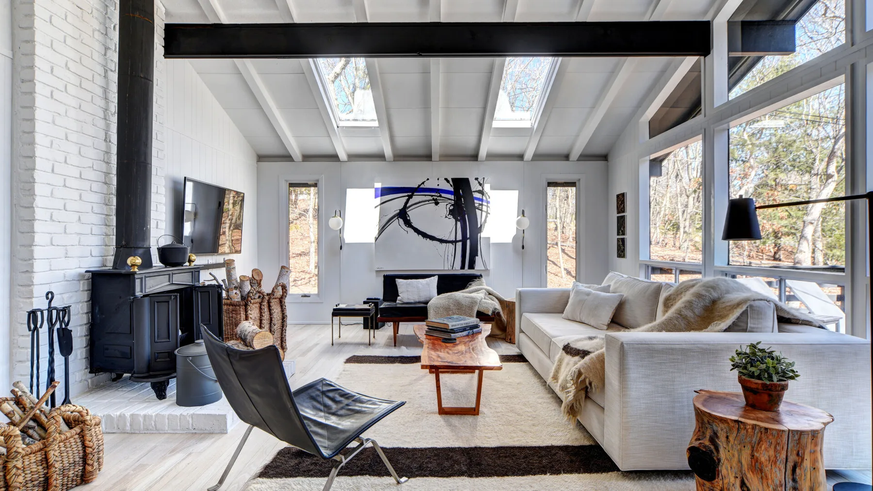 Una sala luminosa con grandes ventanas, asientos y una chimenea.