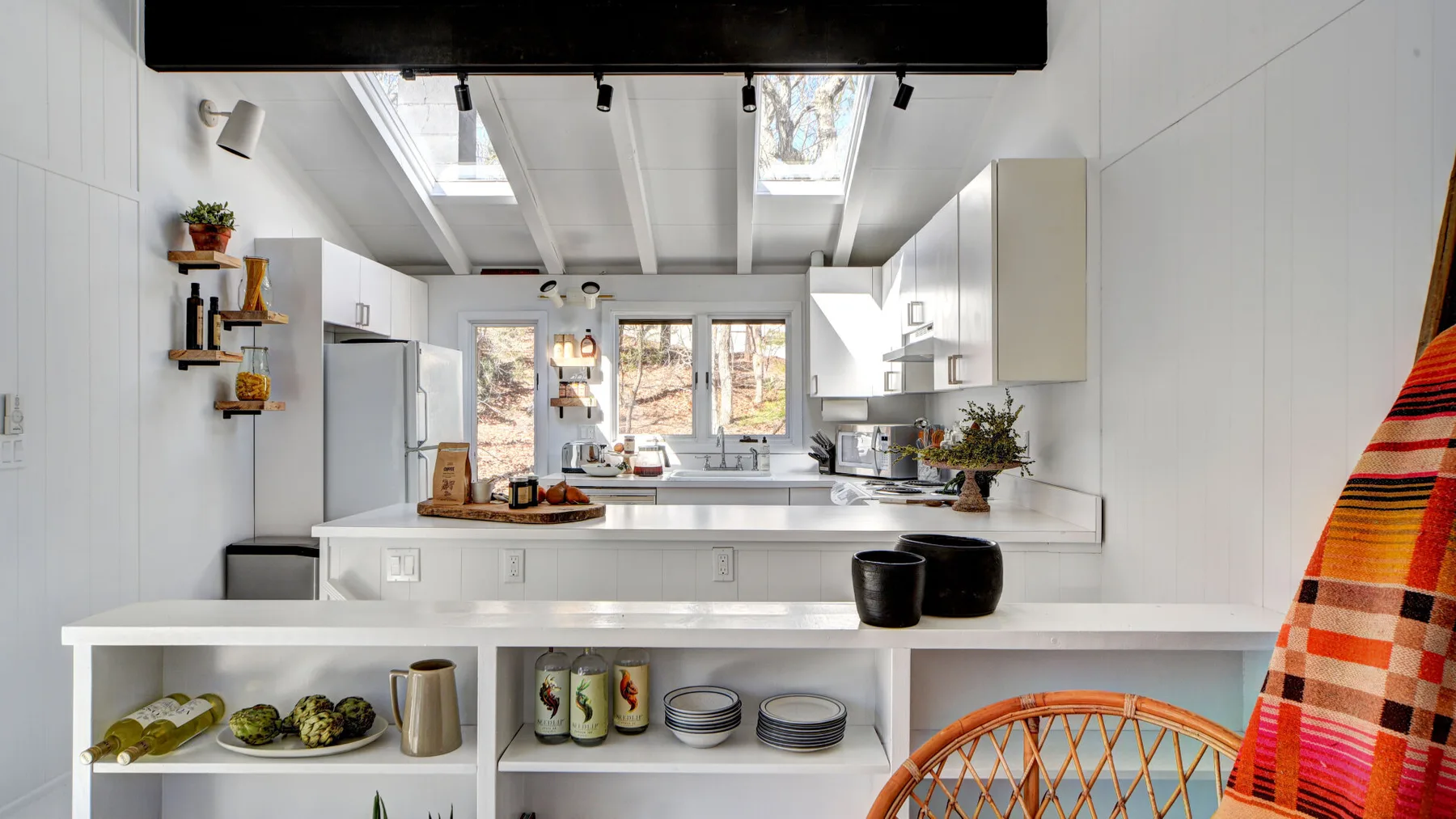 Una cocina luminosa con una isla central, tragaluces y gabinetes blancos.