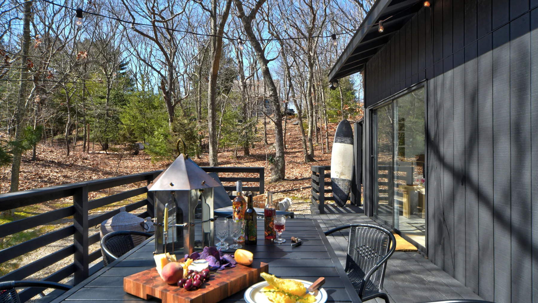Una terraza de comedor al aire libre junto a una zona arbolada, con comida sobre la mesa.