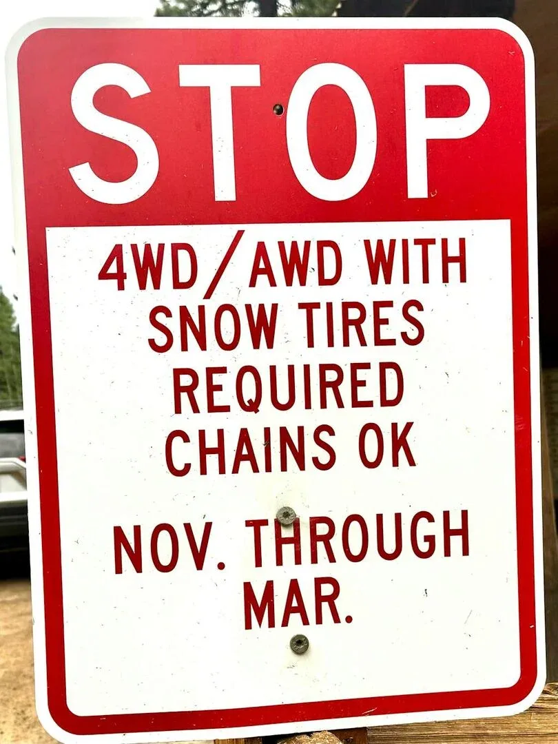 A red stop sign displays winter driving requirements for vehicles.