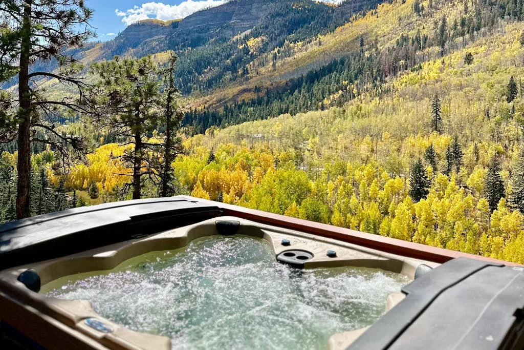 An outdoor hot tub overlooks a forested mountain valley.