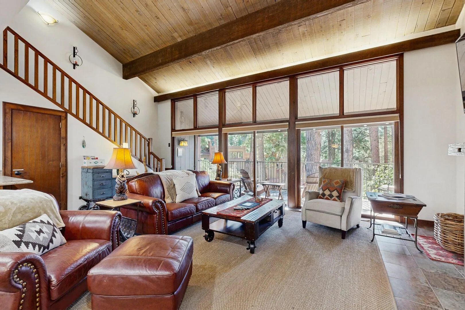 A living room with seating and large windows opening onto a wooded view.