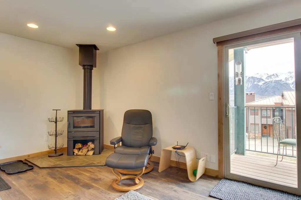 A living room with a wood stove and a recliner beside a glass door.