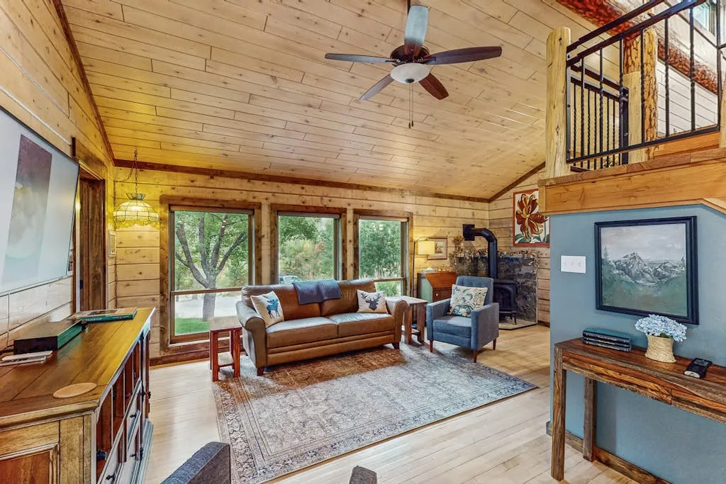 A wood-paneled living room with seating, large windows, and a rug.