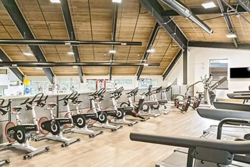 A spacious gym with rows of stationary bikes and workout equipment.