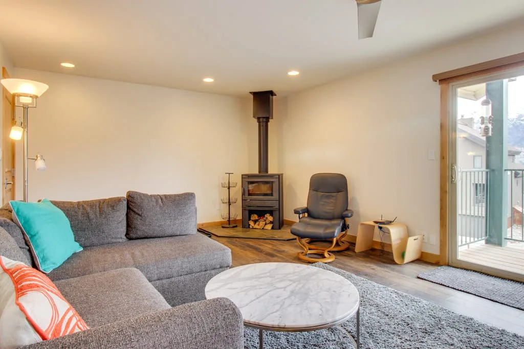 A living room with a gray sectional, round coffee table, and fireplace.
