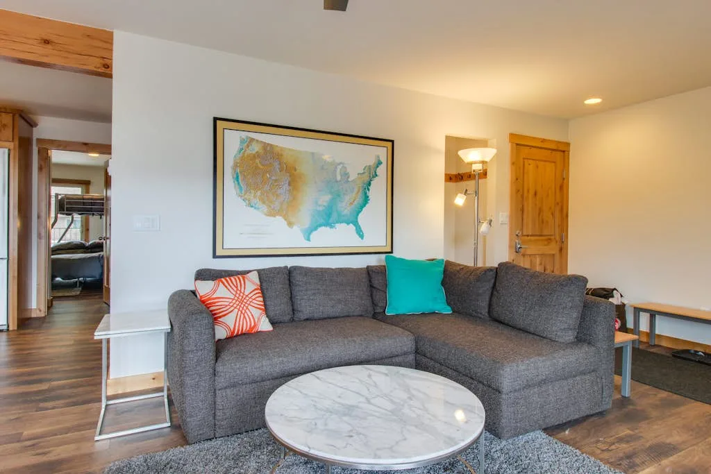 Living room with a gray sectional, round coffee table, and framed wall map.