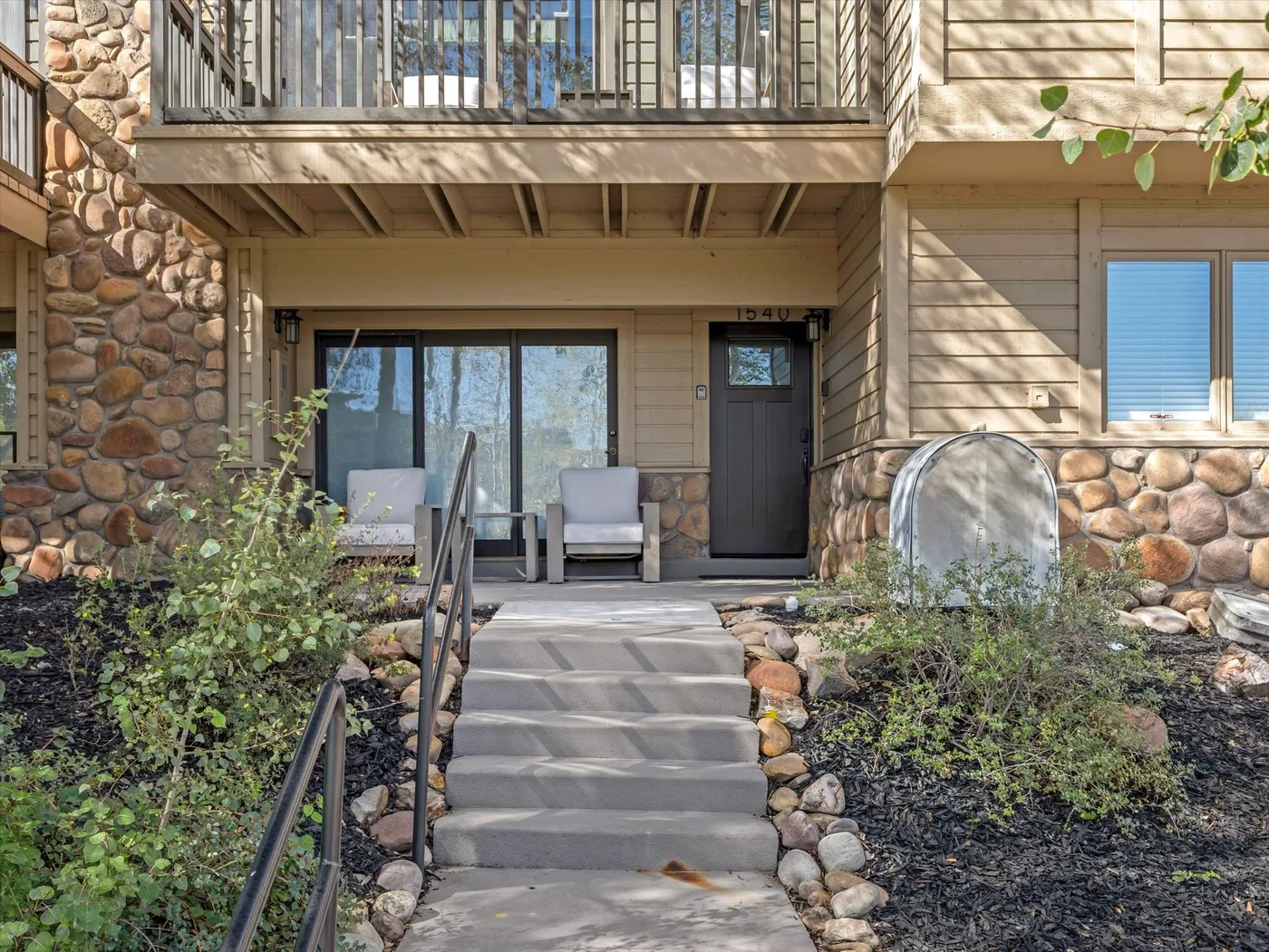 A covered building entrance sits above a short outdoor stairway, with seating beside the door.