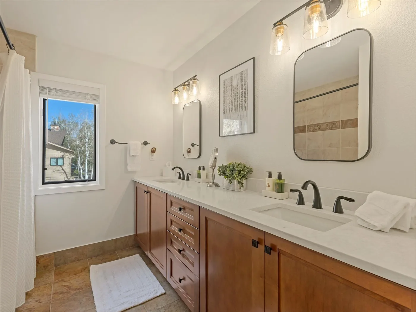 A bathroom vanity with sinks, mirrors, and a window.