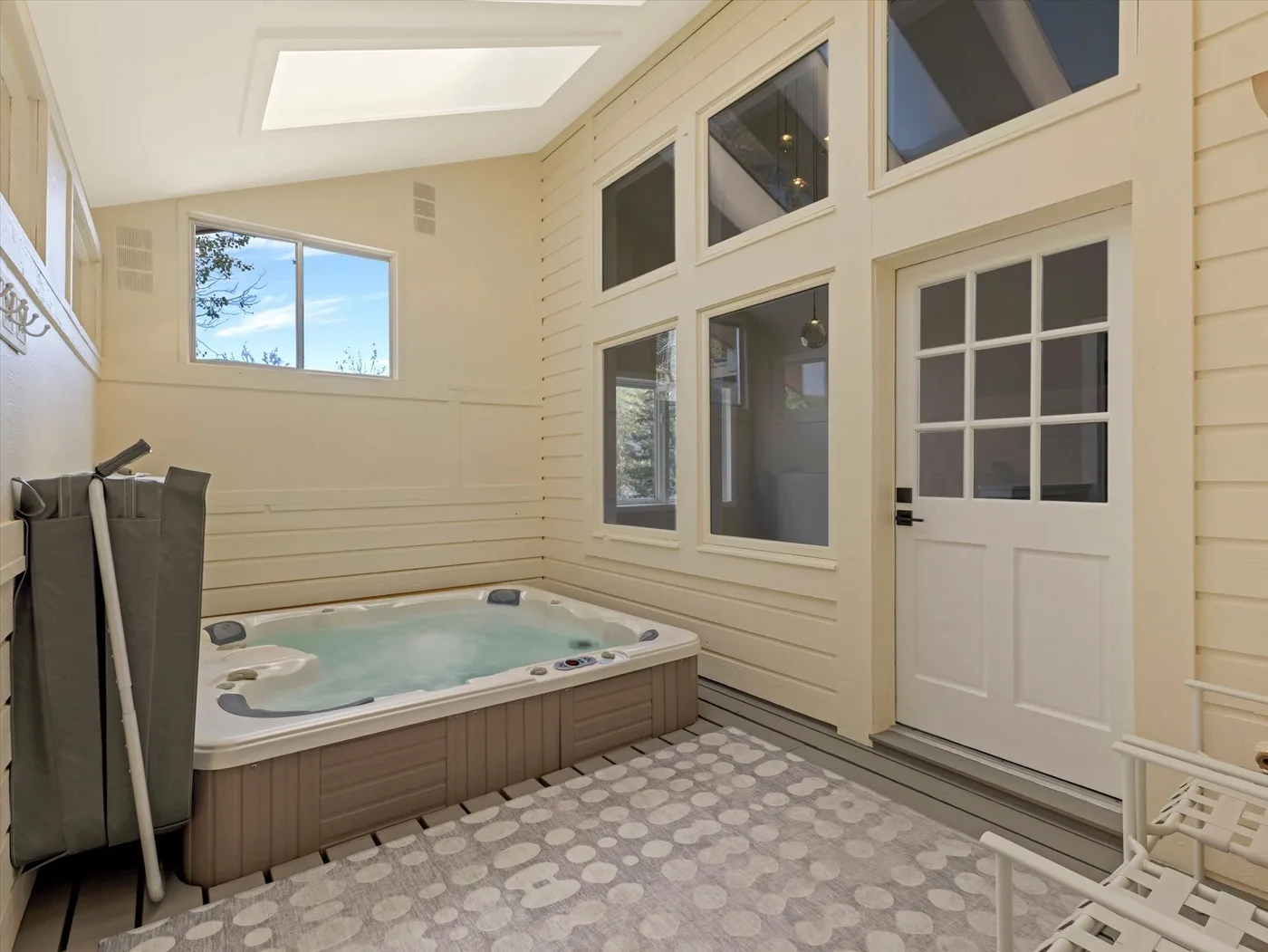 An enclosed indoor hot tub area with windows and a glass-paneled door.
