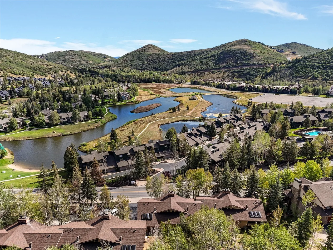 Aerial view of buildings beside a winding river, with green hills in the background.