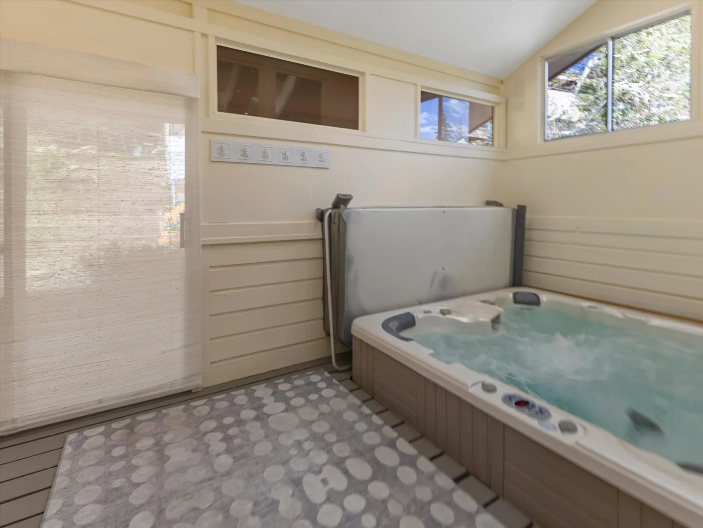 A bright indoor hot tub room with a large jetted tub and high windows.